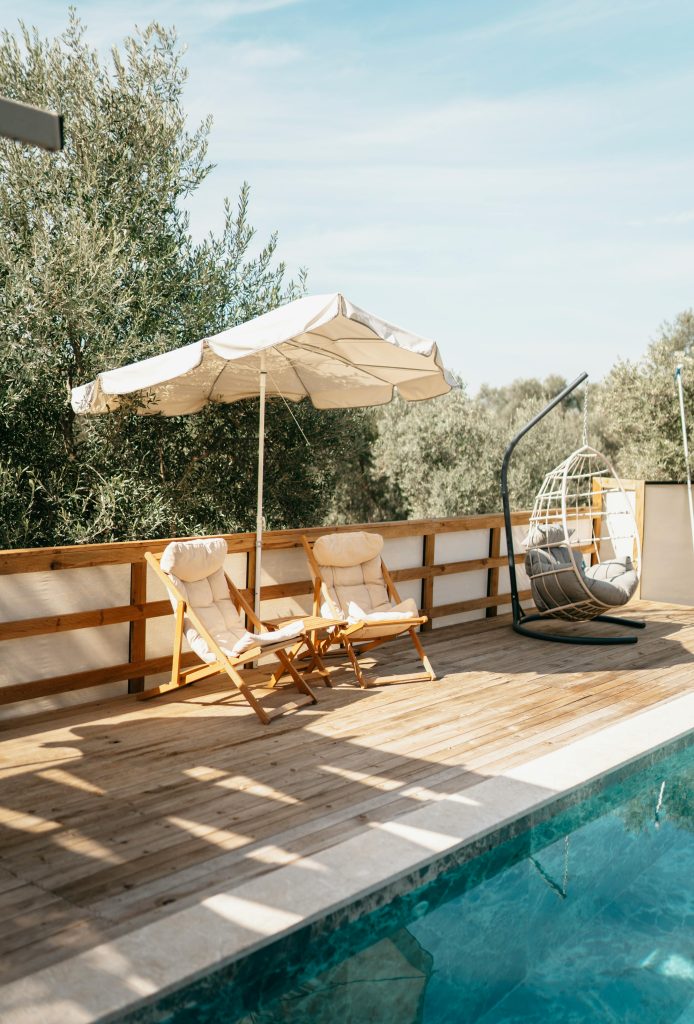 Elegant outdoor terrace in Muğla, Türkiye featuring pool, chairs, and umbrella.