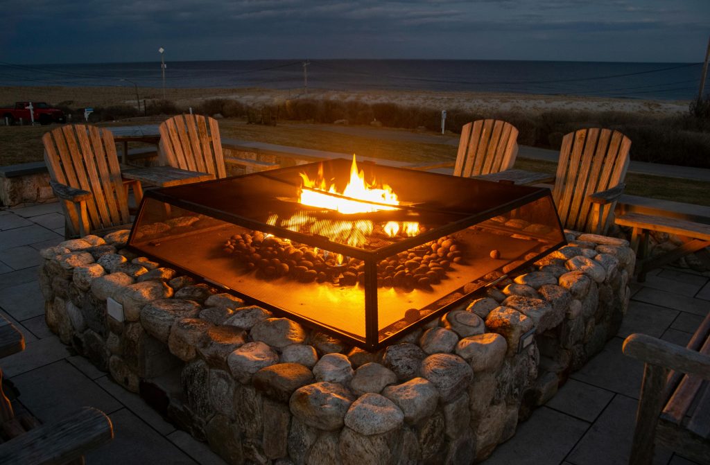 pexels-photo-31148279-31148279 A glowing fire pit surrounded by Adirondack chairs near a beach in Orleans, Massachusetts, USA.