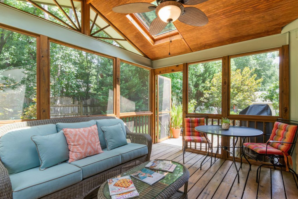 Inviting indoor porch with skylight, wicker sofa, and vibrant decor, perfect for relaxation.