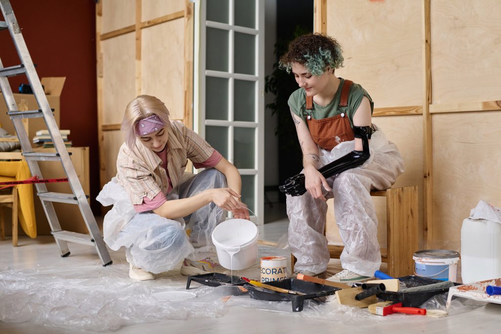 Two young adults showing the difference between home repair vs. remodeling. A diy project painting the walls of their home.